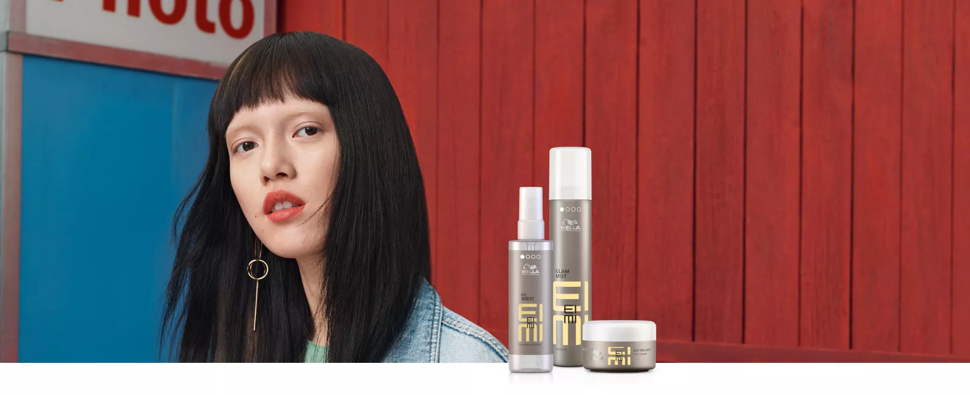 Headshot of a female model with long, straight, black hair, plus 2 silver bottles and 1 pot of EIMI styling products