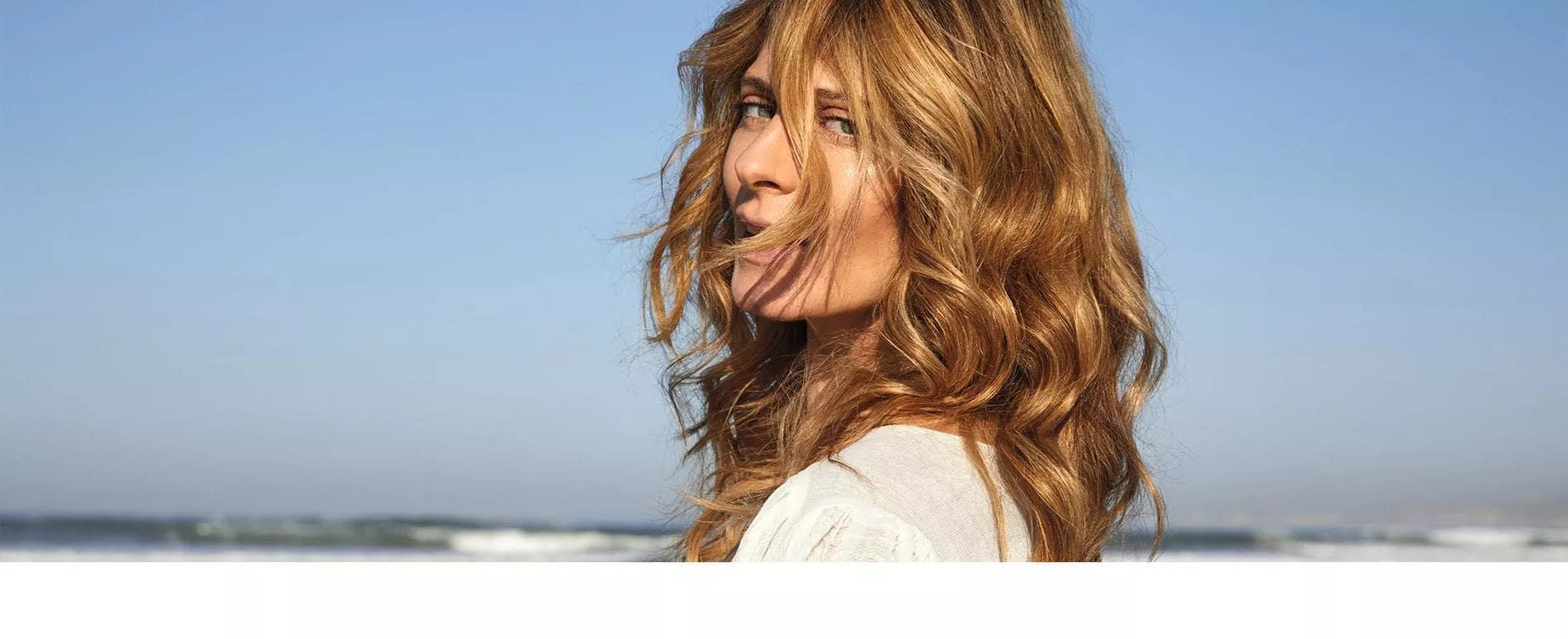 Side portrait of woman on the beach, with curly golden blonde hair created with Illumina Color
