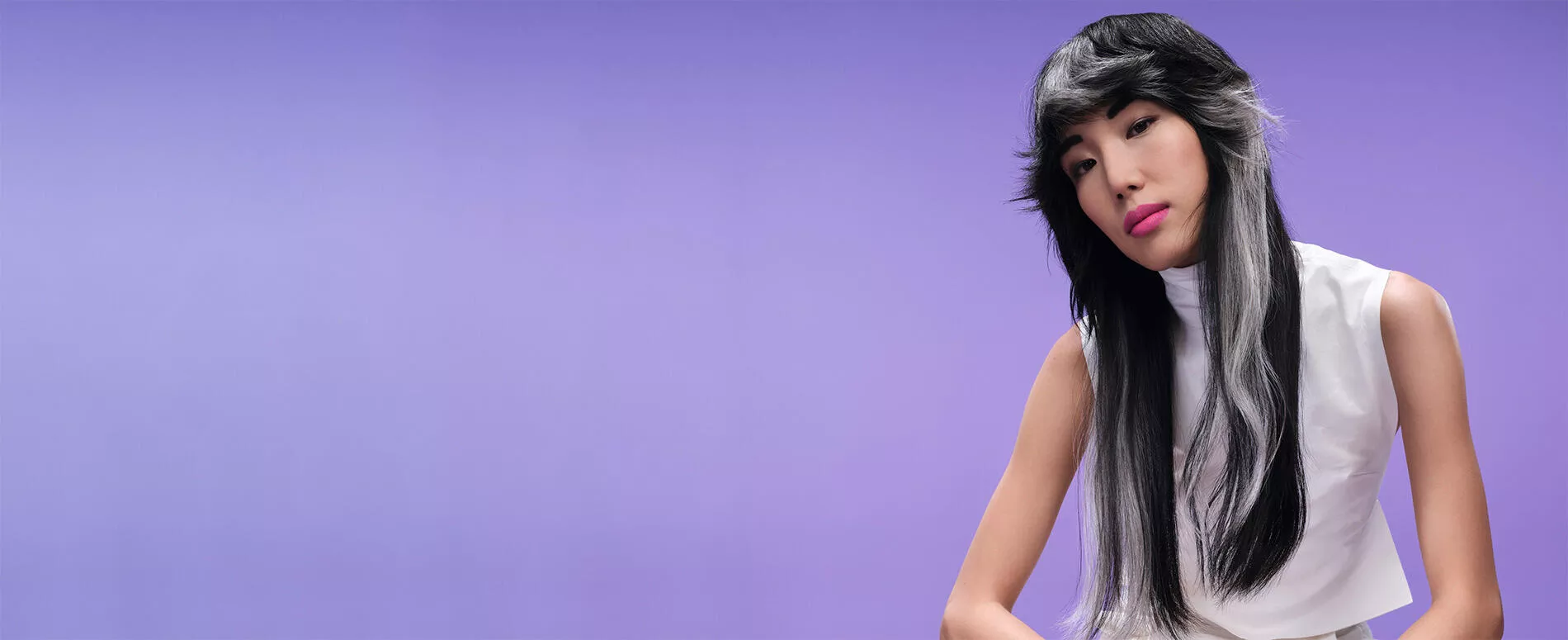Modella dai capelli neri e bianchi realizzati con Monochromatic Blocking su sfondo viola