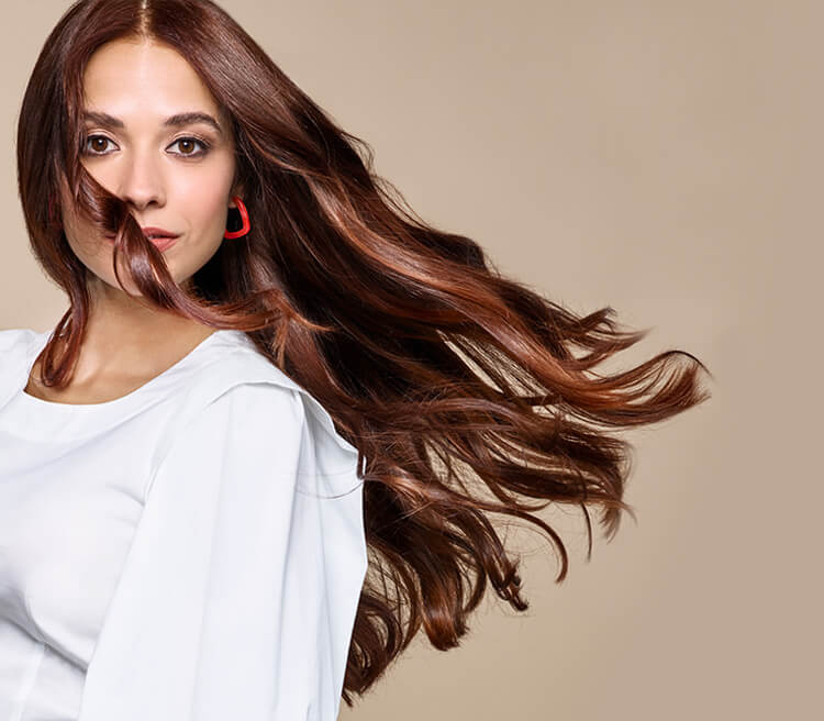 Model with long hair styled in loose curls, created using Wella. 