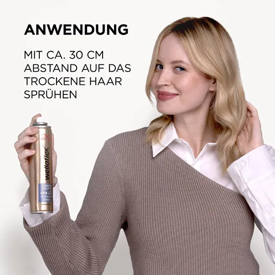 Blondhaariges Model, das sich von Wellaflex das 2-Tages-Volumen Haarspray in die Haare sprüht. Das Haarspray sollte aus einer Entfernung von 30 Zentimetern auf das Haar aufgetragen werden.