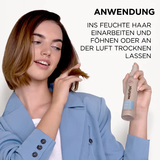 Braunhaariges Model, das sich von Wellaflex das 2-Tages-Volumen Föhnspray in die Haare sprüht. Das Föhnspray in das feuchte Haar einarbeiten und mit einem Föhn trocknen.
